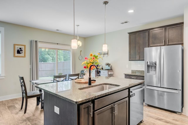 kitchen featuring a sink, light stone counters, visible vents, dark brown cabinets, and appliances with stainless steel finishes