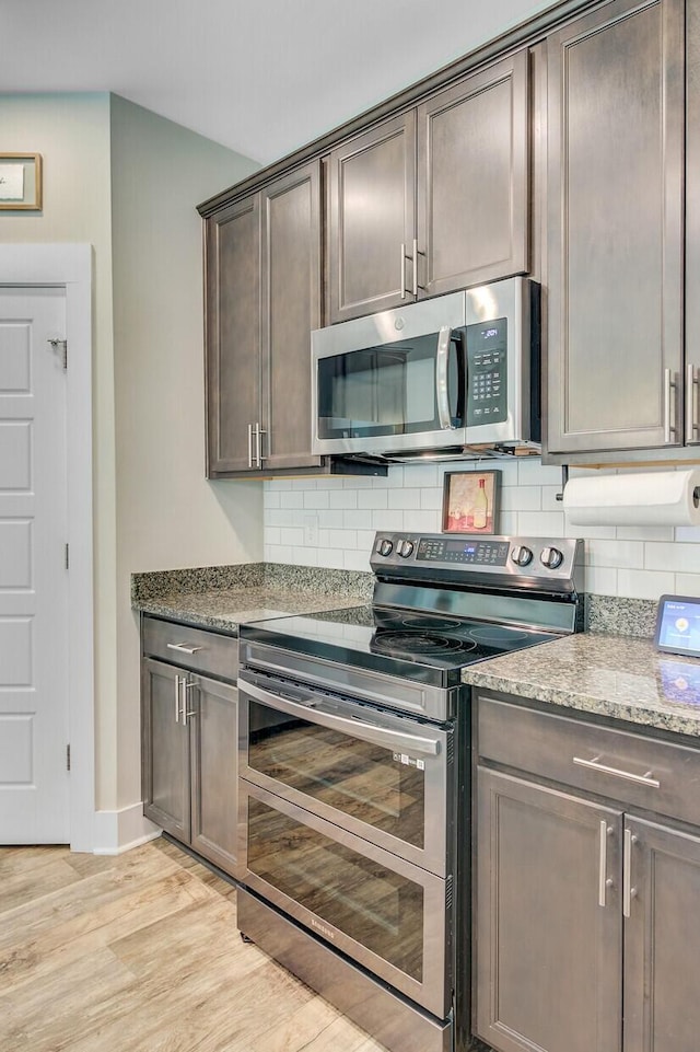 kitchen with tasteful backsplash, appliances with stainless steel finishes, baseboards, dark brown cabinets, and light wood-style floors