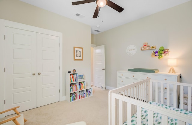 bedroom with a closet, a nursery area, visible vents, and carpet floors