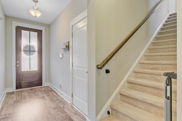 entrance foyer featuring light wood-type flooring, baseboards, and stairs