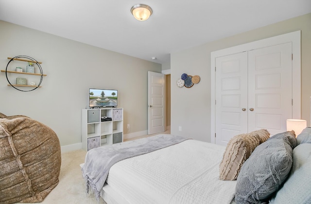 bedroom with light carpet, a closet, and baseboards