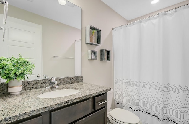 bathroom featuring toilet, vanity, and a shower with curtain
