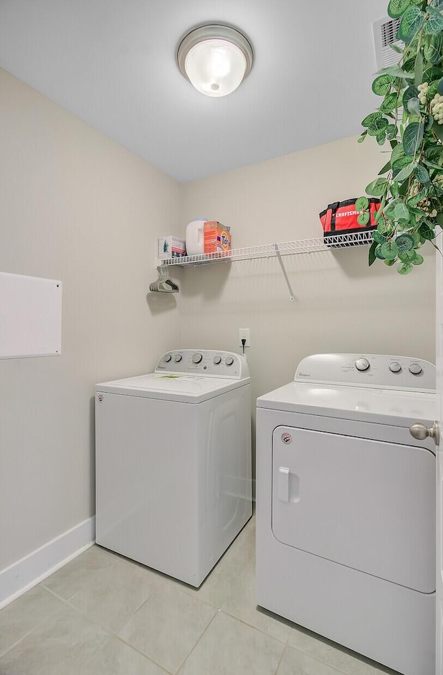 washroom with washing machine and dryer, light tile patterned floors, laundry area, visible vents, and baseboards