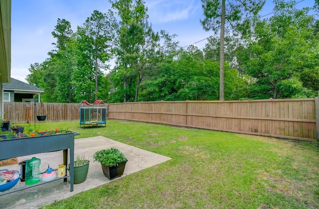 view of yard featuring a fenced backyard, a trampoline, and a patio