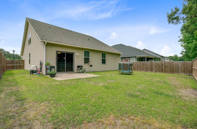 back of property featuring a lawn, a trampoline, a patio area, and a fenced backyard