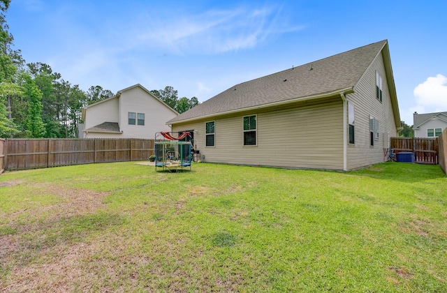 back of property featuring a fenced backyard, a trampoline, cooling unit, and a lawn