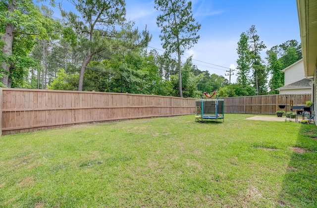 view of yard featuring a trampoline and a fenced backyard