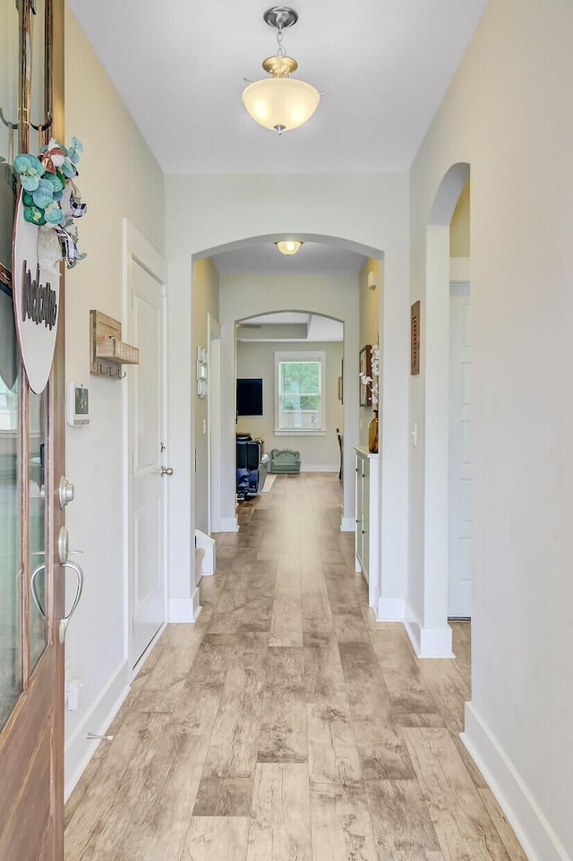 hall featuring arched walkways and baseboards