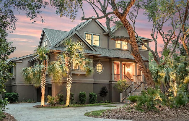 view of front facade featuring driveway, stairway, and stucco siding