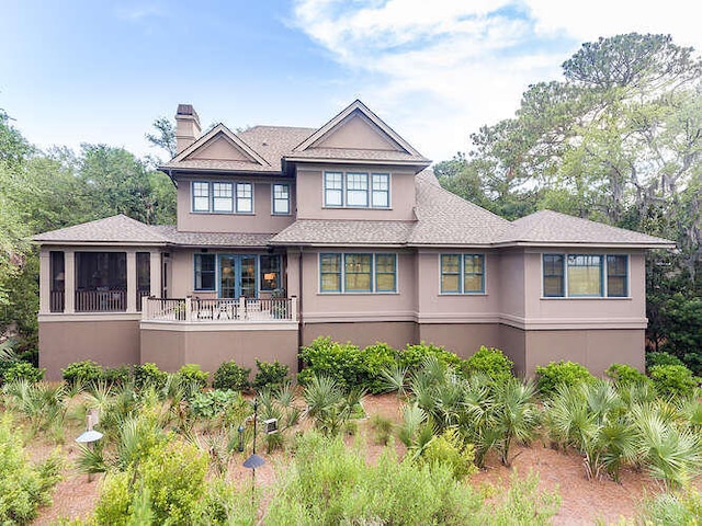 view of front of house with a chimney, a sunroom, and stucco siding