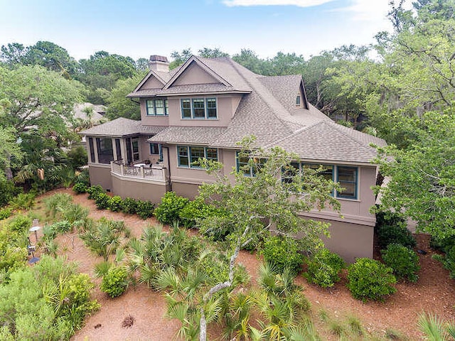 view of front of house with roof with shingles, a chimney, and stucco siding