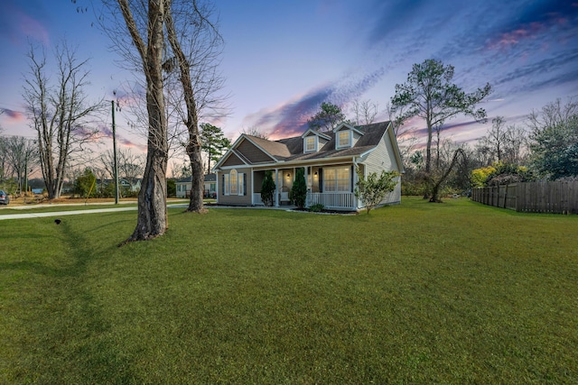 view of front of house featuring fence, a porch, and a yard