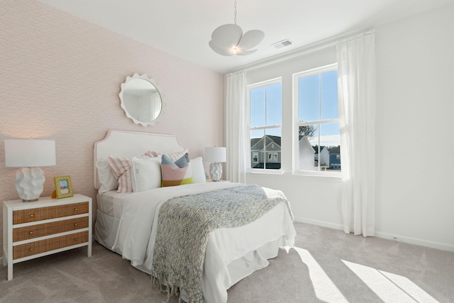 carpeted bedroom featuring wallpapered walls, baseboards, and visible vents