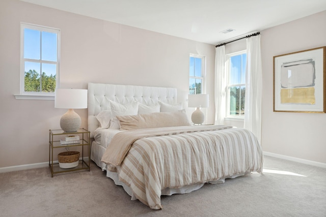 carpeted bedroom featuring multiple windows, baseboards, and visible vents