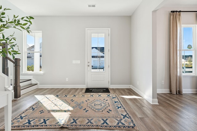 entrance foyer featuring visible vents, stairway, baseboards, and wood finished floors