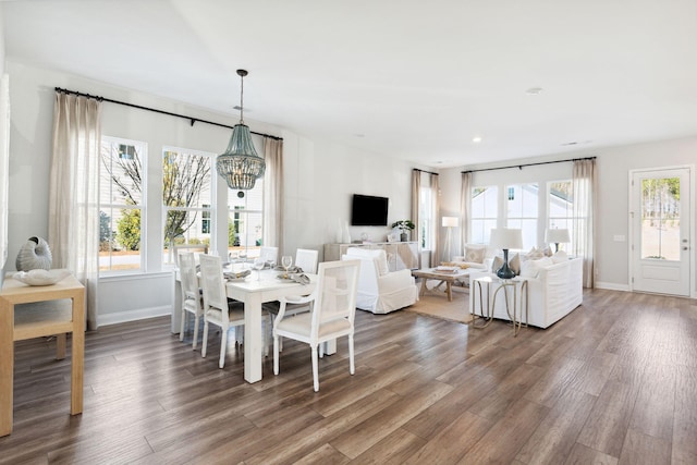 dining room with an inviting chandelier, wood finished floors, baseboards, and a wealth of natural light