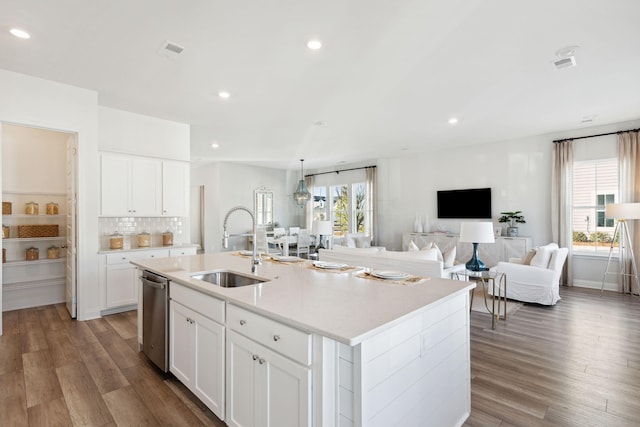 kitchen with a sink, visible vents, wood finished floors, and light countertops