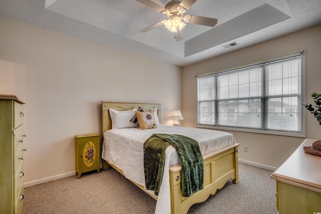 bedroom with a raised ceiling, light carpet, and baseboards