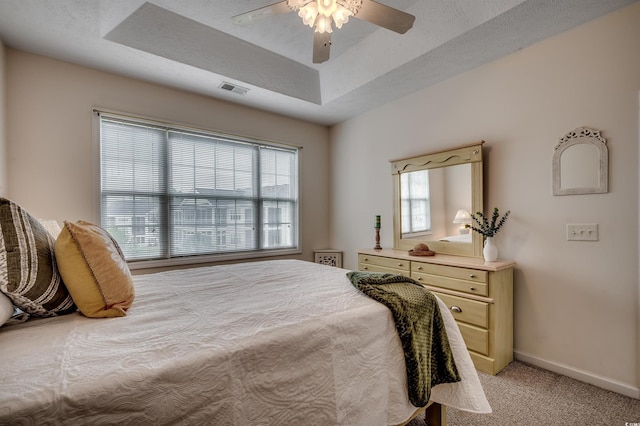 bedroom with a textured ceiling, light colored carpet, a ceiling fan, baseboards, and visible vents