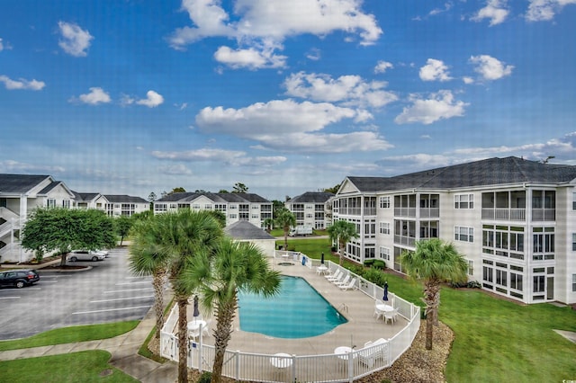 community pool with a yard, a patio area, and fence