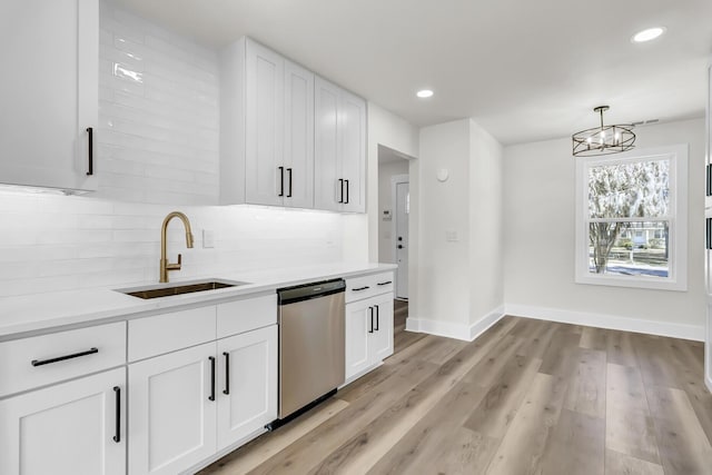 kitchen featuring a sink, white cabinetry, light wood-style floors, stainless steel dishwasher, and backsplash