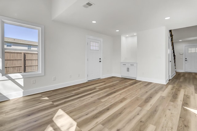 interior space with a barn door, baseboards, visible vents, light wood-type flooring, and recessed lighting