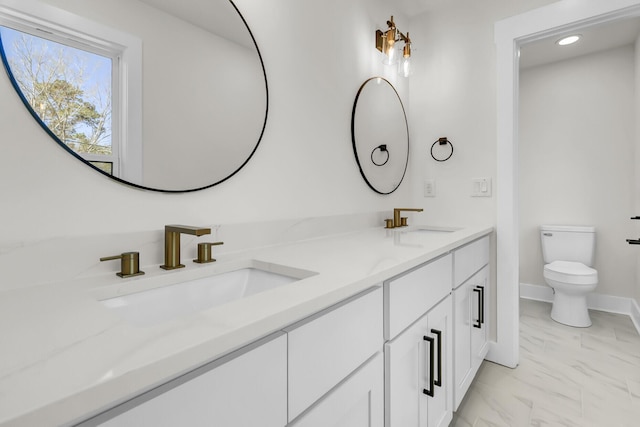 full bathroom featuring marble finish floor, double vanity, a sink, and toilet