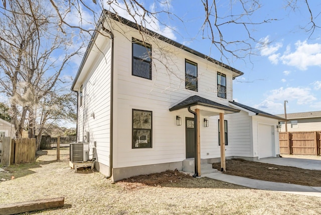 view of front facade with central air condition unit, a garage, fence, and concrete driveway