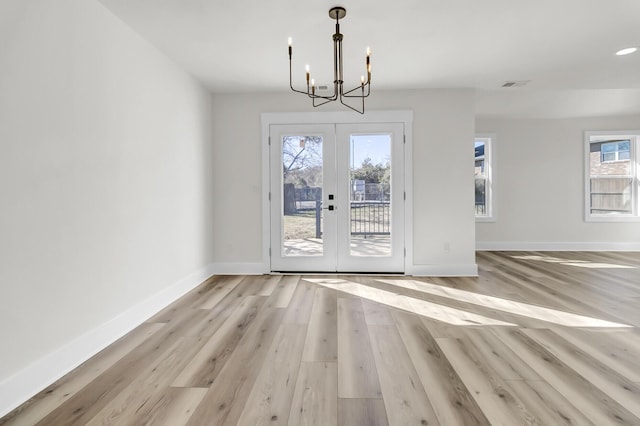 unfurnished dining area featuring wood finished floors, visible vents, baseboards, french doors, and an inviting chandelier