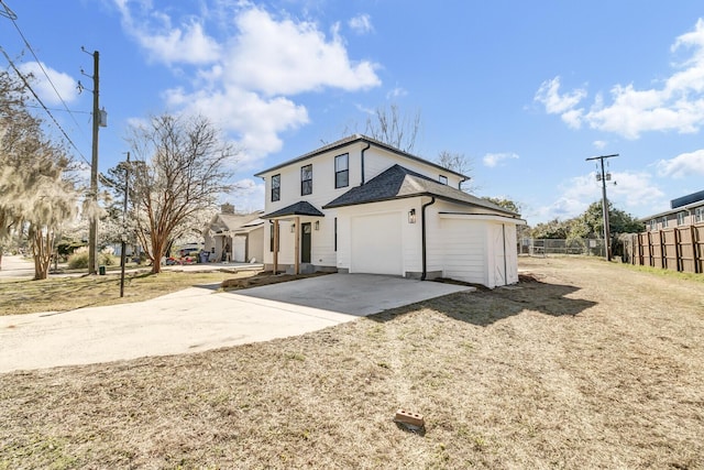 traditional-style home featuring concrete driveway, roof with shingles, fence, and an attached garage