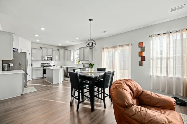 dining space with sink, dark hardwood / wood-style floors, and a chandelier