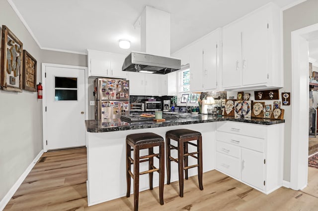 kitchen featuring light hardwood / wood-style floors, kitchen peninsula, island exhaust hood, stainless steel refrigerator, and white cabinetry