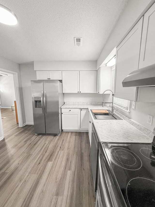 kitchen featuring white cabinetry, stainless steel appliances, a textured ceiling, light hardwood / wood-style flooring, and sink