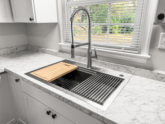 details featuring light stone countertops, white cabinetry, and sink