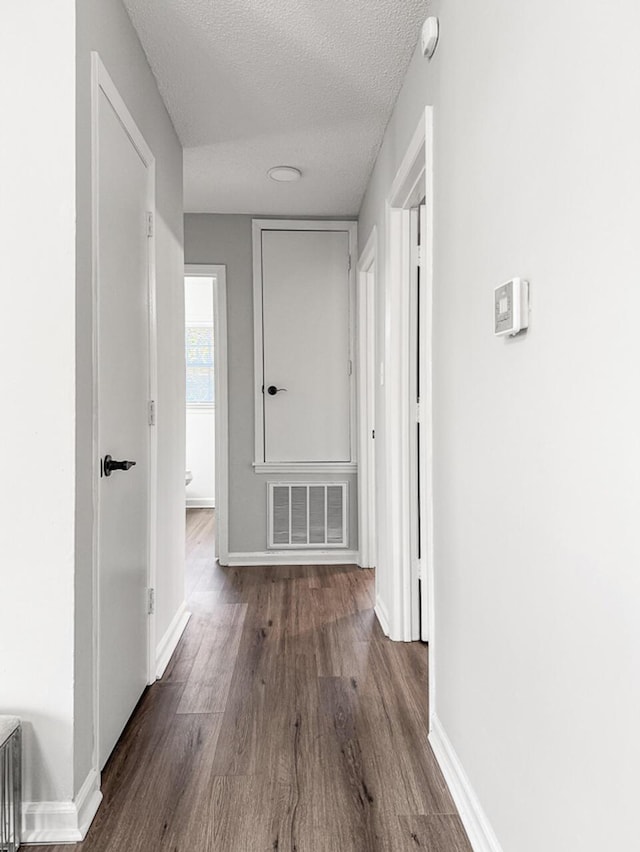 hall with a textured ceiling and hardwood / wood-style floors