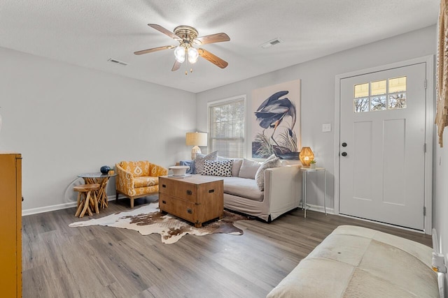 living room featuring a textured ceiling, ceiling fan, and wood-type flooring