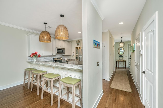 kitchen featuring white cabinetry, stainless steel appliances, backsplash, kitchen peninsula, and decorative light fixtures