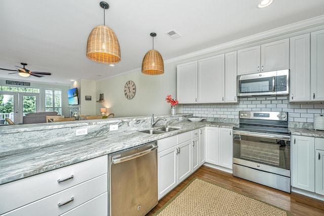 kitchen with white cabinets, sink, stainless steel appliances, and hanging light fixtures