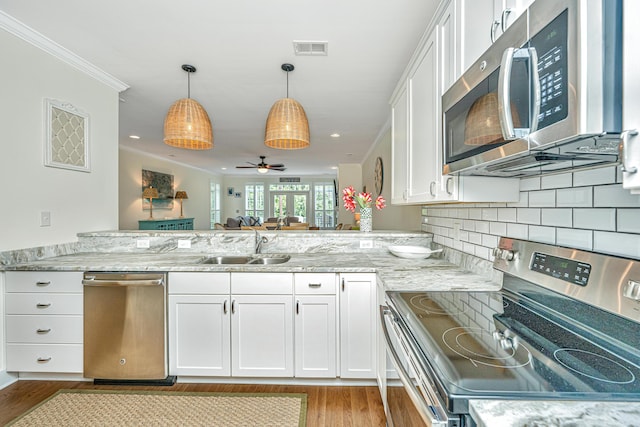 kitchen featuring white cabinets, crown molding, sink, hanging light fixtures, and stainless steel appliances