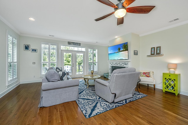 living room featuring dark hardwood / wood-style flooring, ornamental molding, a tiled fireplace, and french doors