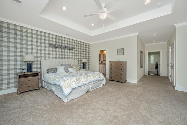 bedroom featuring connected bathroom, light colored carpet, a raised ceiling, and ceiling fan