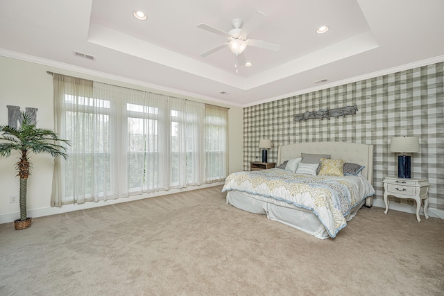 carpeted bedroom featuring ceiling fan, a raised ceiling, and ornamental molding