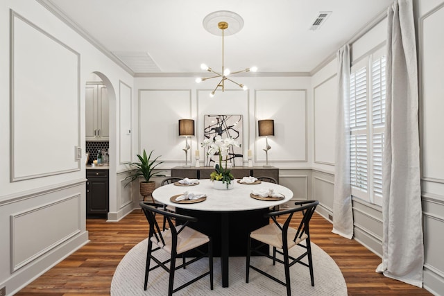 dining space with ornamental molding, dark hardwood / wood-style flooring, and a notable chandelier