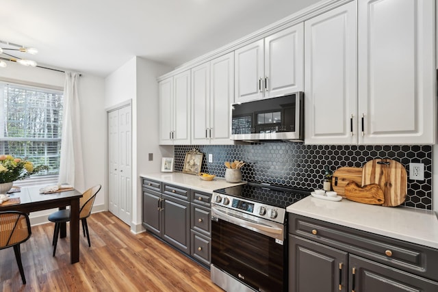 kitchen with stainless steel appliances, backsplash, white cabinets, and light wood-type flooring