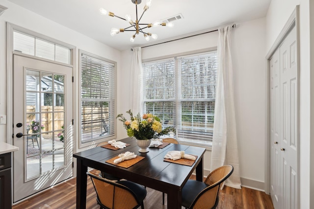 dining space featuring dark wood-type flooring and a chandelier