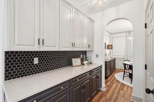 bar featuring wood-type flooring, white cabinets, and decorative backsplash