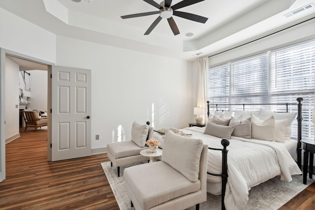 bedroom featuring dark hardwood / wood-style floors, ceiling fan, and a tray ceiling