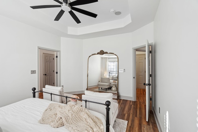 bedroom featuring ceiling fan, a tray ceiling, and dark hardwood / wood-style floors