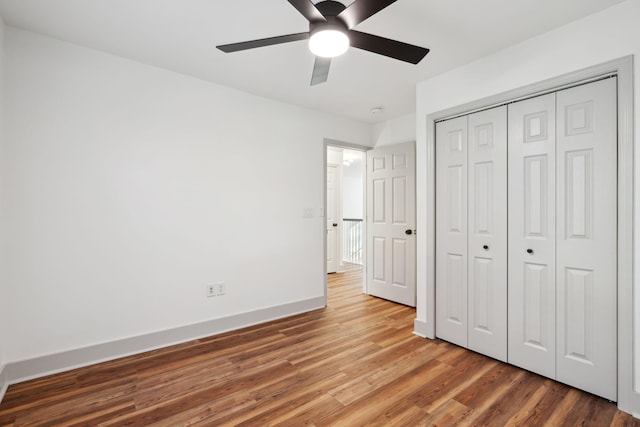 unfurnished bedroom featuring hardwood / wood-style floors, ceiling fan, and a closet