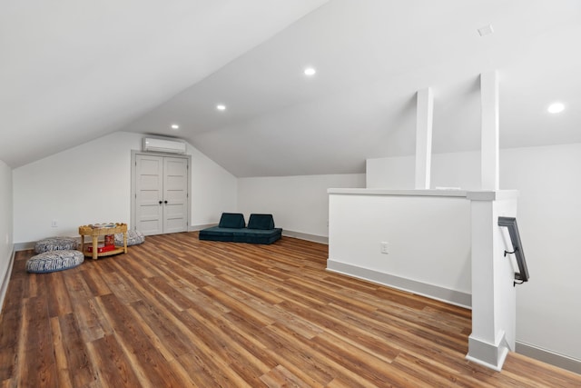 bonus room with hardwood / wood-style floors, vaulted ceiling, and an AC wall unit